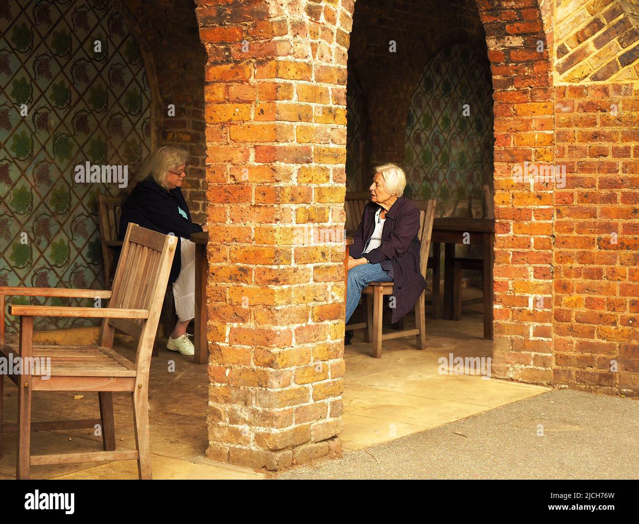 london08-04 2017.due donne anziane chiacchierano amabilmente sul portico di un parco pubblico a Londra, anche se sembrano essere separate da una colonna di mattone Foto Stock