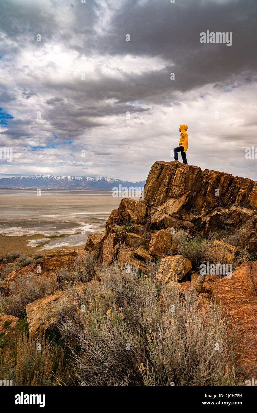 Un ragazzo in piedi su un'alta roccia che guarda su un letto asciutto del lago nello Utah Foto Stock