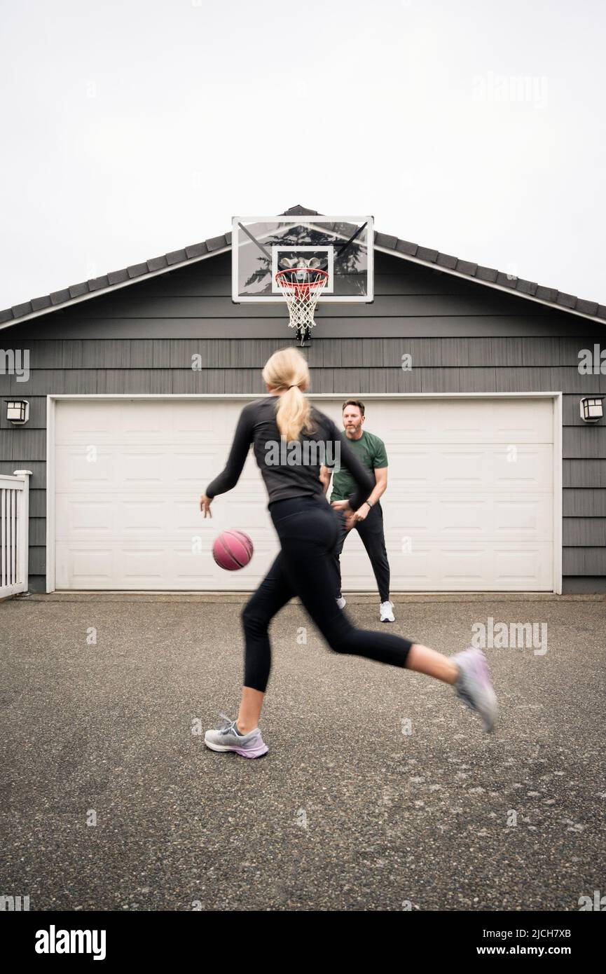 Padre e figlia Teen che lavorano sulle abilità di basket nel vialetto Foto Stock