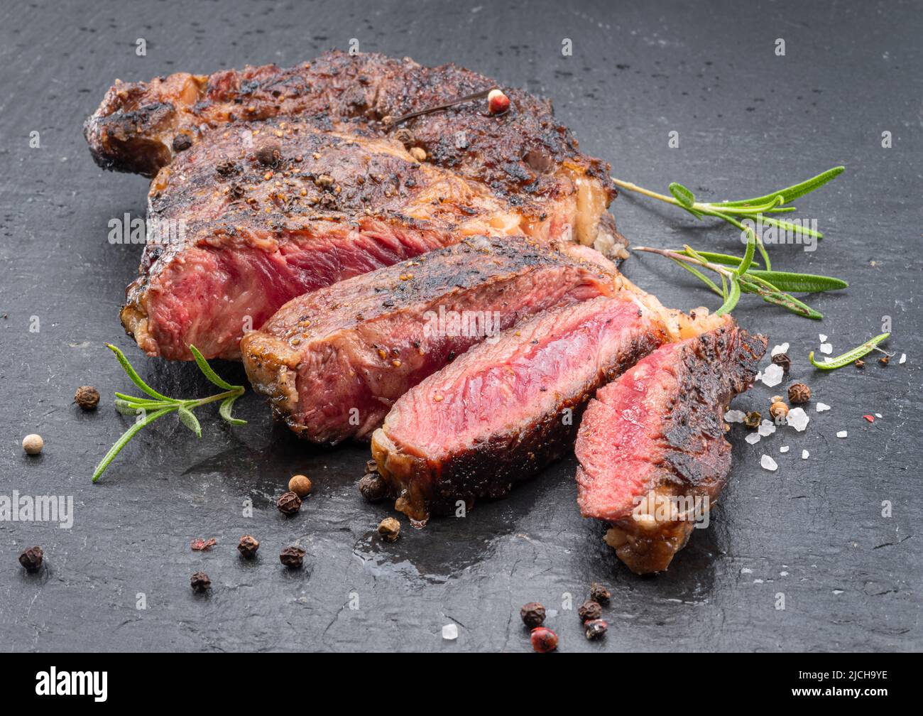 Bistecca di ribeye mediamente rara alla griglia su piastra di pietra grigia. Foto Stock