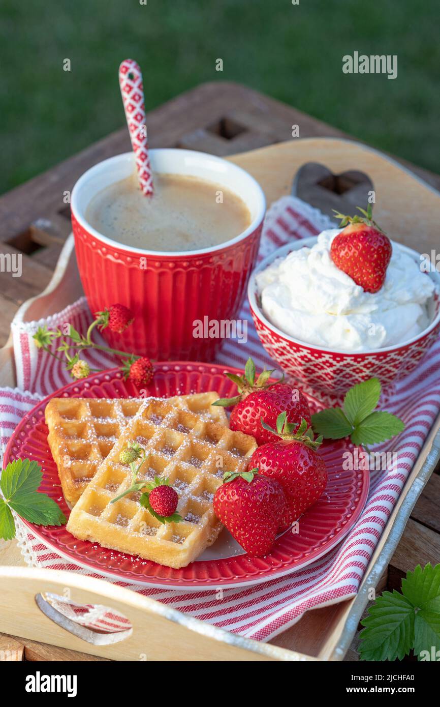 waffle e fragole fresche sul piatto, tazza di caffè e panna montata Foto Stock