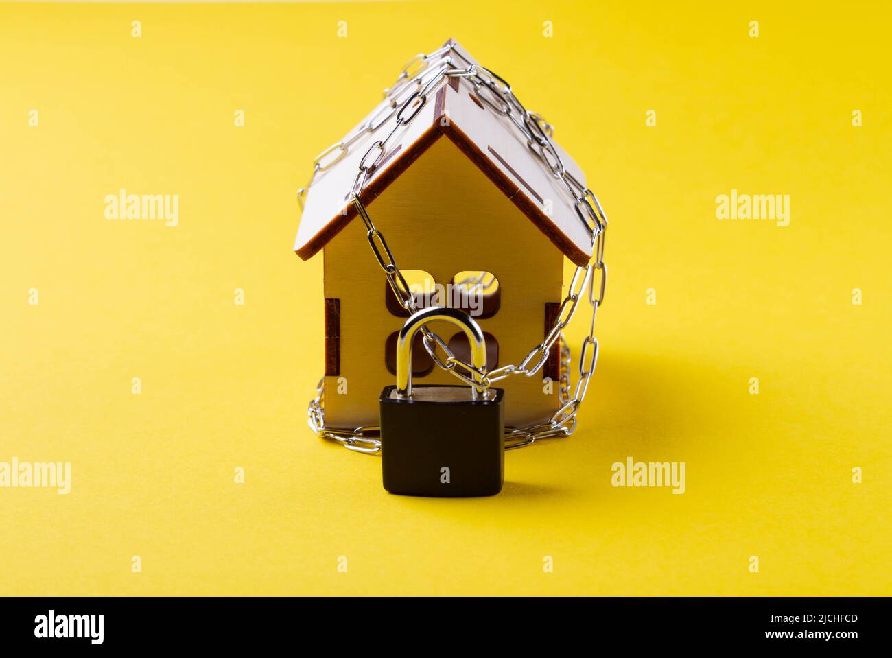 Arresto dell'alloggiamento. Casa del castello. Piccola casa giocattolo e una catena con un lucchetto. Sfratto per mancato pagamento. La porta chiusa a chiave della casa. Foto Stock