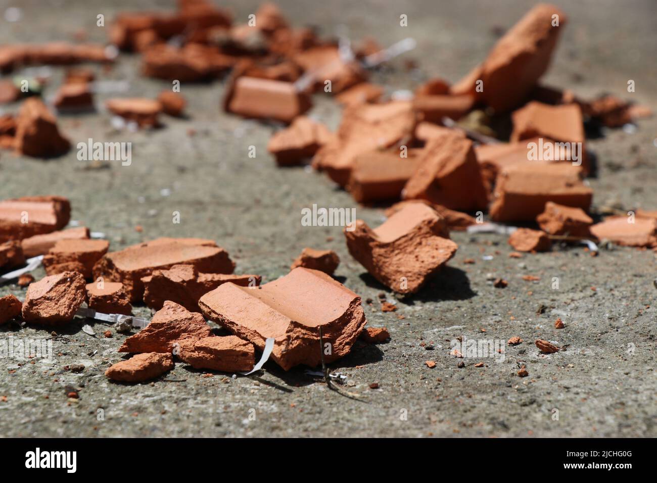 Tegole rotte in pezzi sparse a terra con luce naturale per esterni Foto Stock