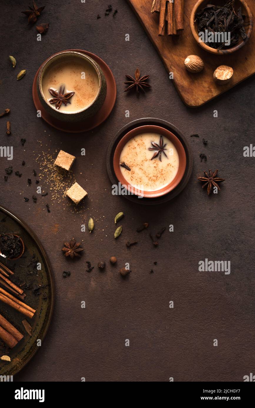 Masala Chai Tea in tazza di ceramica con ingredienti. Tradizionale indiano speziato tè nero con latte su sfondo rustico scuro, spazio copia. Foto Stock