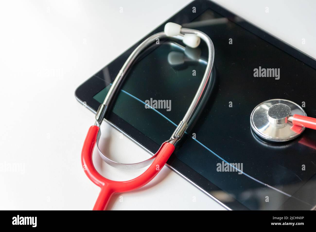 Lo stetoscopio rosso sul dispositivo tablet nero mostra le cartelle cliniche e le registrazioni digitali dei pazienti sulla sicurezza dei dati cloud per i medici digitali e il recupero digitale Foto Stock
