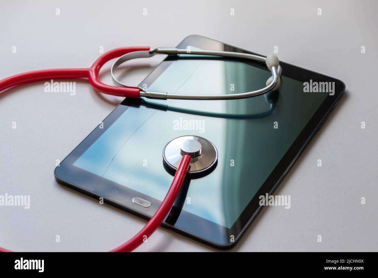 Lo stetoscopio rosso sul dispositivo tablet nero mostra le cartelle cliniche e le registrazioni digitali dei pazienti sulla sicurezza dei dati cloud per i medici digitali e il recupero digitale Foto Stock