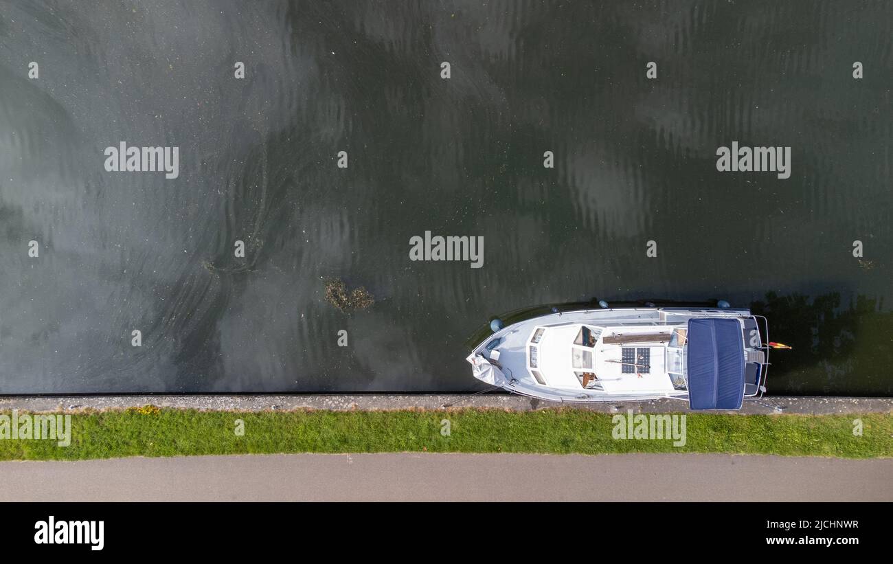 Foto dall'alto in basso del drone aereo di un piccolo yacht di lusso ancorato al molo sul fiume. Foto di alta qualità Foto Stock