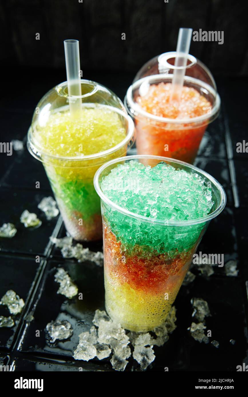 Tre colorati drink slush su sfondo nero. Rinfrescanti bevande estive su una superficie scura in fotografia verticale. Foto Stock