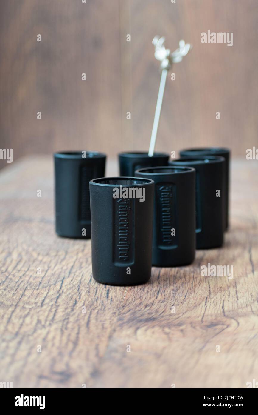 Tiraspol, Moldavia - 26 maggio 2022: Bicchieri di Jagermeister. Bicchieri neri di liquore tradizionale Jagermeister su sfondo di legno. Foto Stock