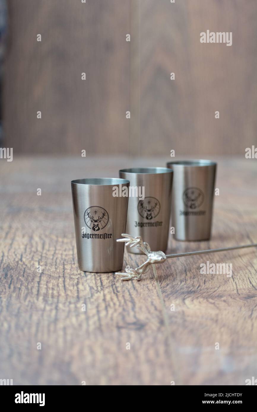 Tiraspol, Moldavia - 26 maggio 2022: Bicchieri di Jagermeister. Bicchieri in metallo di liquore tradizionale Jagermeister su sfondo di legno. Foto Stock