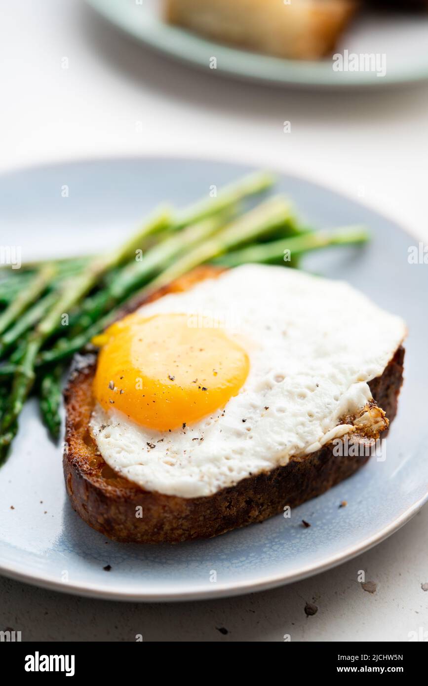 Uova fritte con pane tostato e asparagi verdi. Idee per il pranzo veloce, colazione sana, cibo estivo. Foto Stock