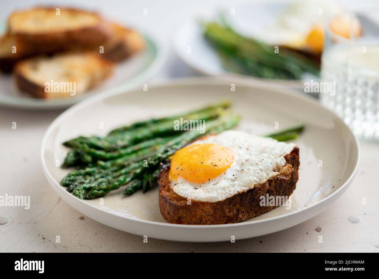 Uova fritte con pane tostato e asparagi verdi. Idee per il pranzo veloce, colazione sana, cibo estivo. Foto Stock