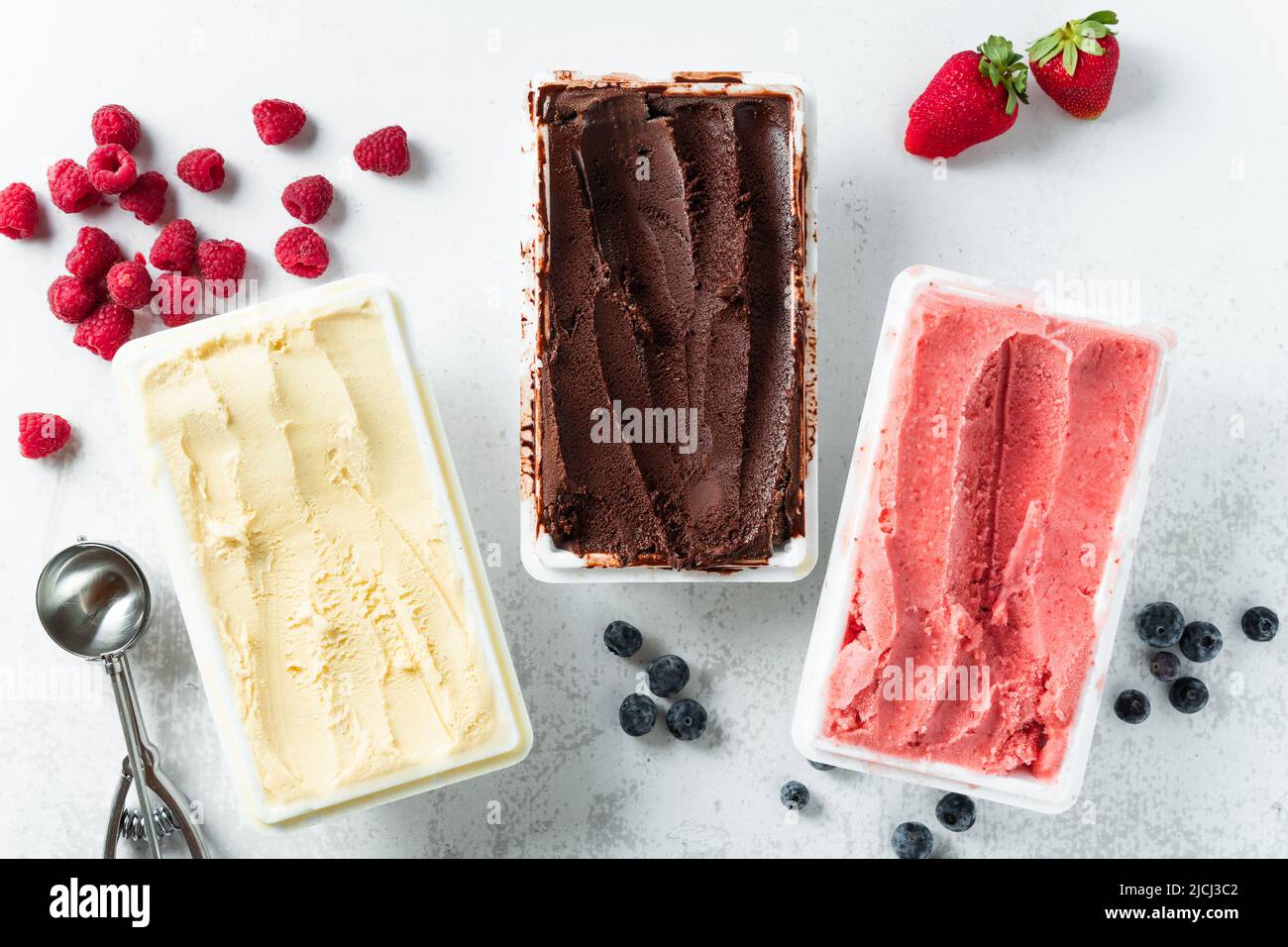 Vero gelato artigianale italiano in confezione: Cioccolato, fragole, vaniglia con frutti di bosco e un cucchiaio Foto Stock