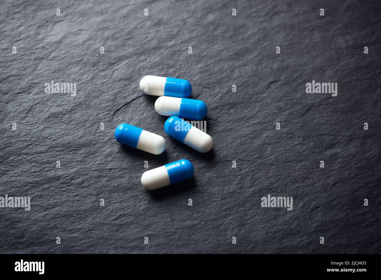 Supplementi sportivi (creatina capsule) su sfondo di pietra scura. Primo piano. Spazio di copia. Foto Stock