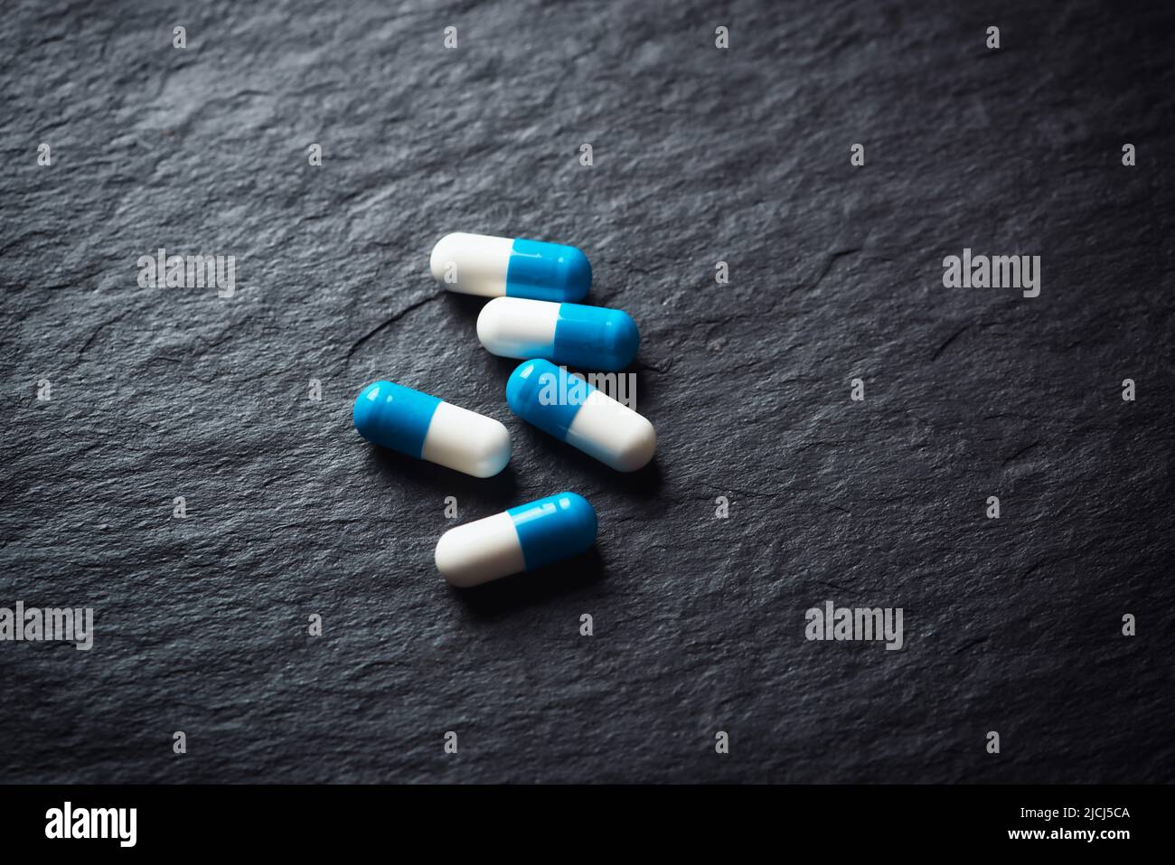 Supplementi sportivi (creatina capsule) su sfondo di pietra scura. Primo piano. Spazio di copia. Foto Stock