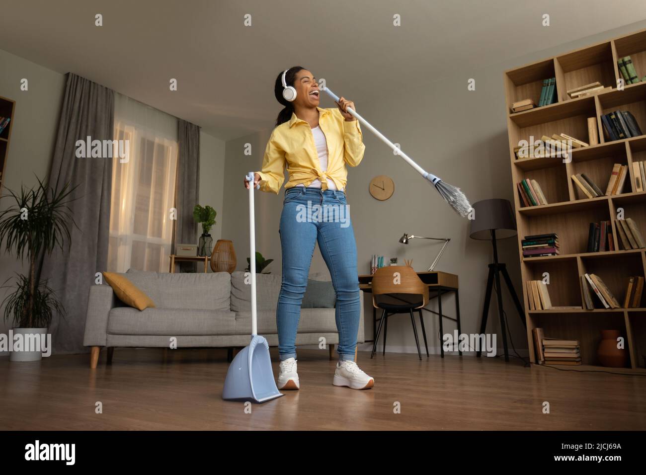 Happy African Female Waving Fun Sweep Floor Singing a casa Foto Stock