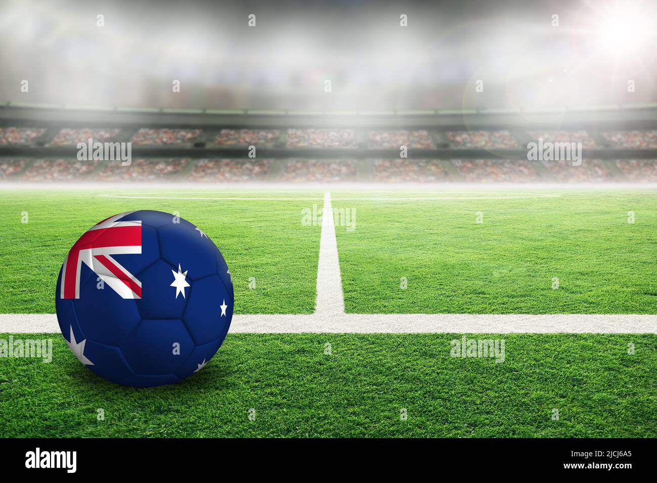 Calcio australiano in uno stadio all'aperto luminoso con bandiera australiana dipinta. Fuoco su primo piano e pallone di calcio con profondità di campo poco profonda su ba Foto Stock
