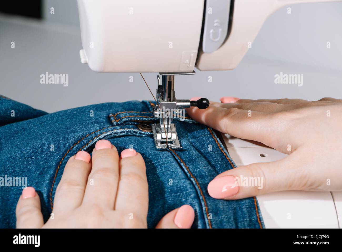 Donna su misura lavora su macchina da cucire. Tessuto di tenuta per le mani. Giornata mondiale dei sarti. Primo piano del processo di cucitura. Riparazione abbigliamento domestico. Foto Stock