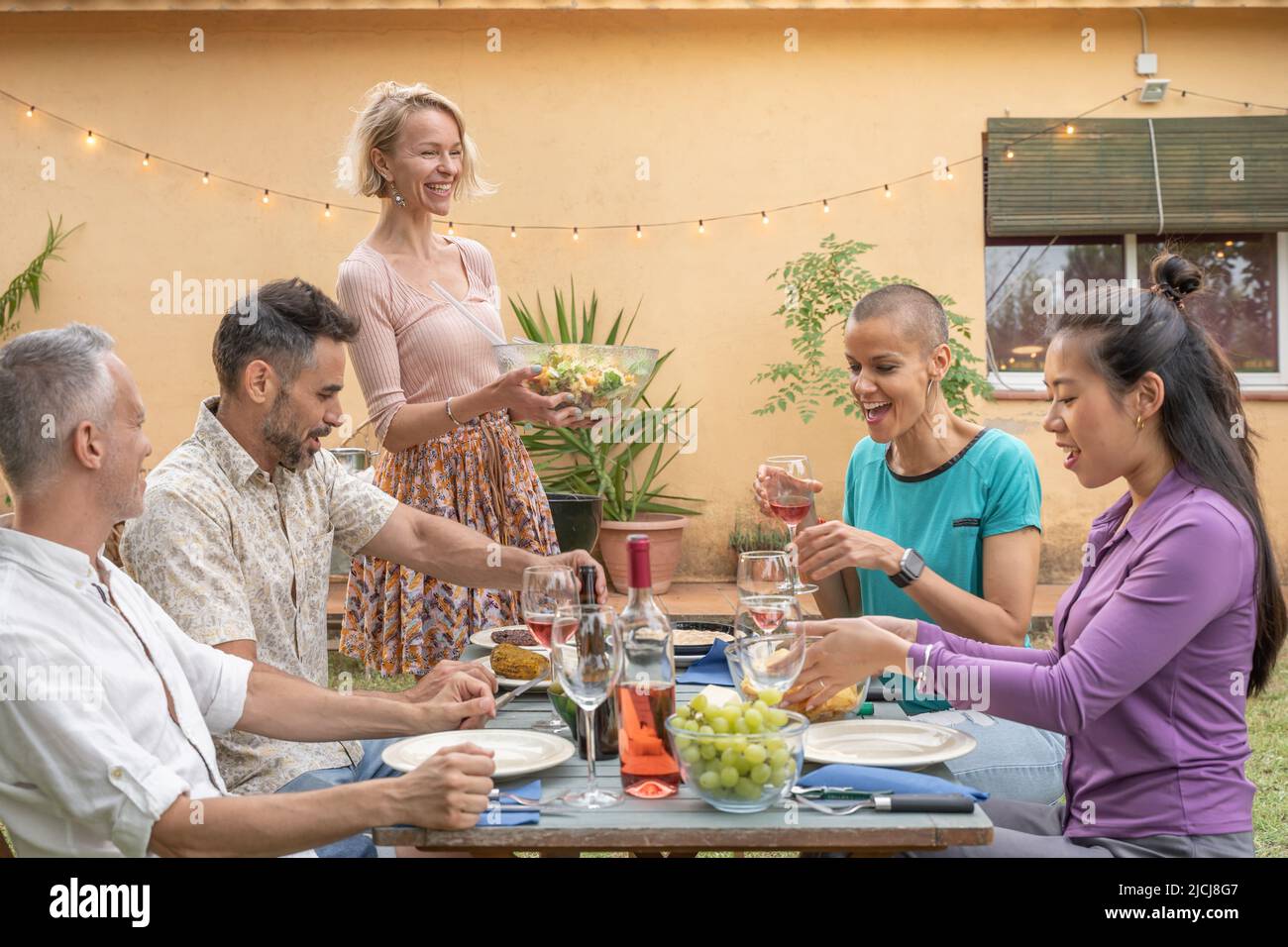 Amici maturi felici che cenano insieme in barbecue cena partito in estate. Sorrisi, concetto di allegria. Foto Stock