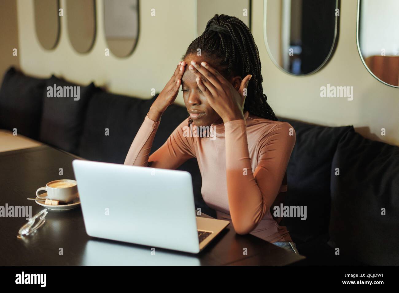 Esausta, arrabbiata gara mista afro americano businesswoman, freelance lavoro seduta online utilizzando il laptop in ufficio creativo Foto Stock