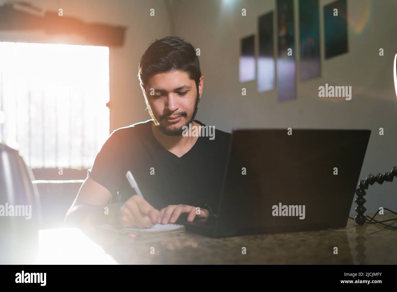 Giovane uomo che fa i compiti seduti alla scrivania con un moderno portatile, uomo che fa un piano per il futuro e la creazione di elenco di cose da fare. Foto Stock