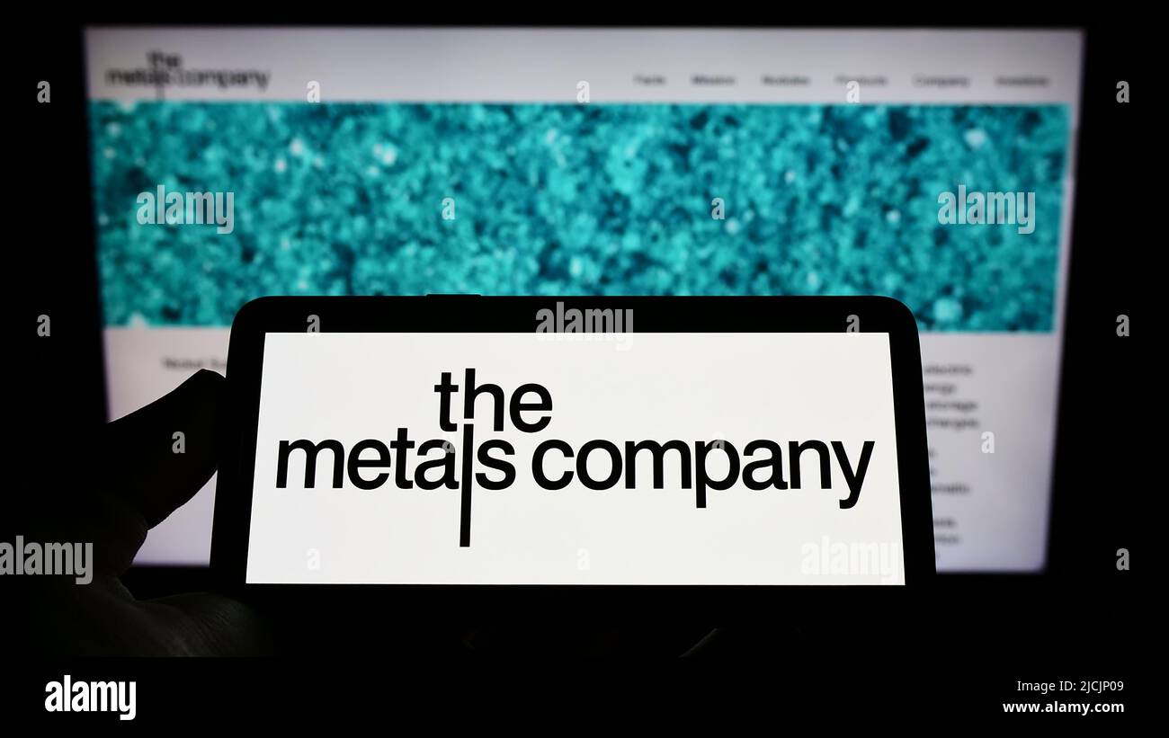 Persona che tiene uno smartphone con il logo della società mineraria TMC The Metals Company Inc. Sullo schermo di fronte al sito Web. Mettere a fuoco sul display del telefono. Foto Stock