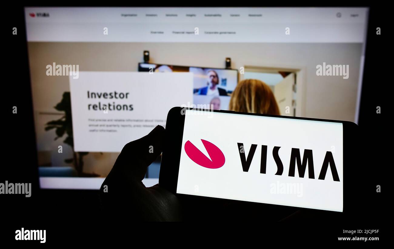 Persona che tiene lo smartphone con il logo della società software norvegese Visma SULLO schermo di fronte al sito Web. Mettere a fuoco sul display del telefono. Foto Stock