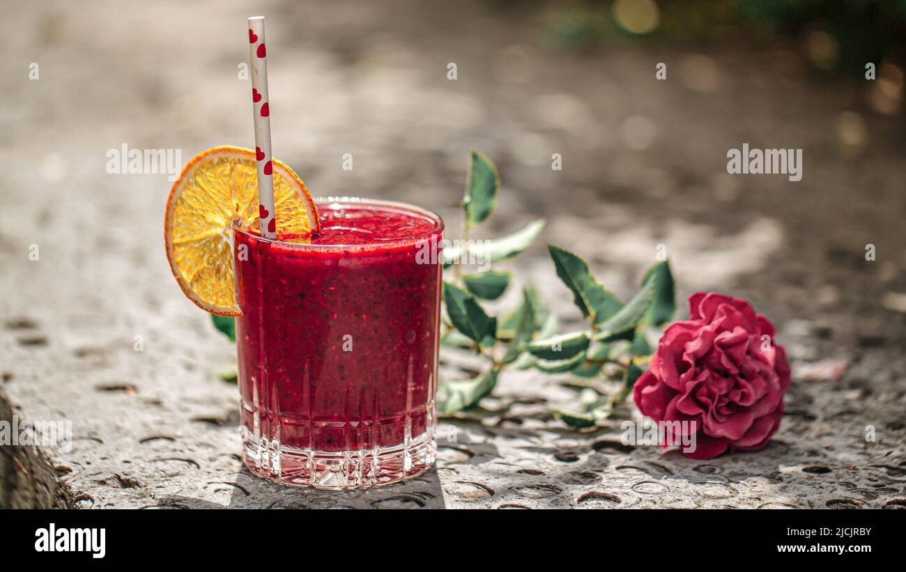 Bicchiere di frullato fresco alla bacche con fetta d'arancia Foto Stock