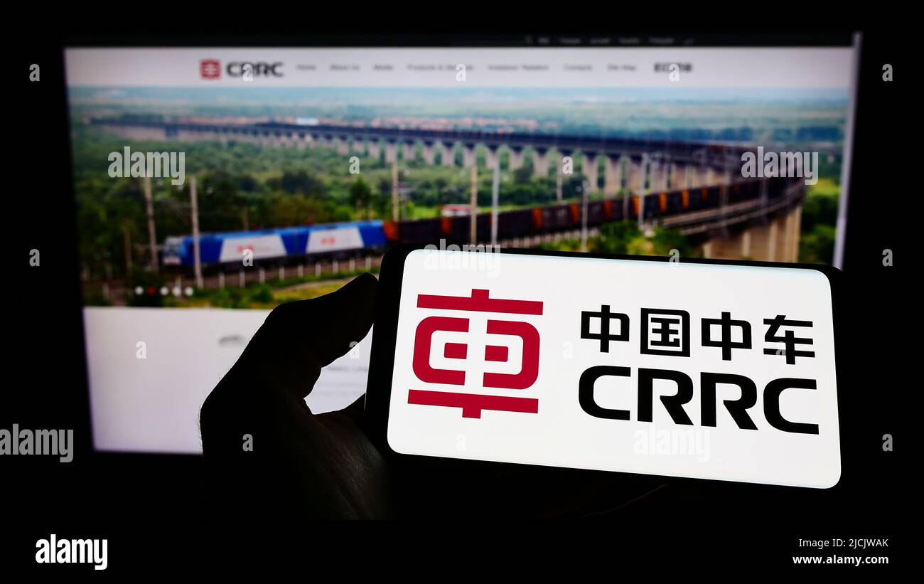 Persona che tiene il telefono cellulare con il logo della società cinese CRRC Corporation Limited sullo schermo di fronte alla pagina web aziendale. Mettere a fuoco sul display del telefono. Foto Stock