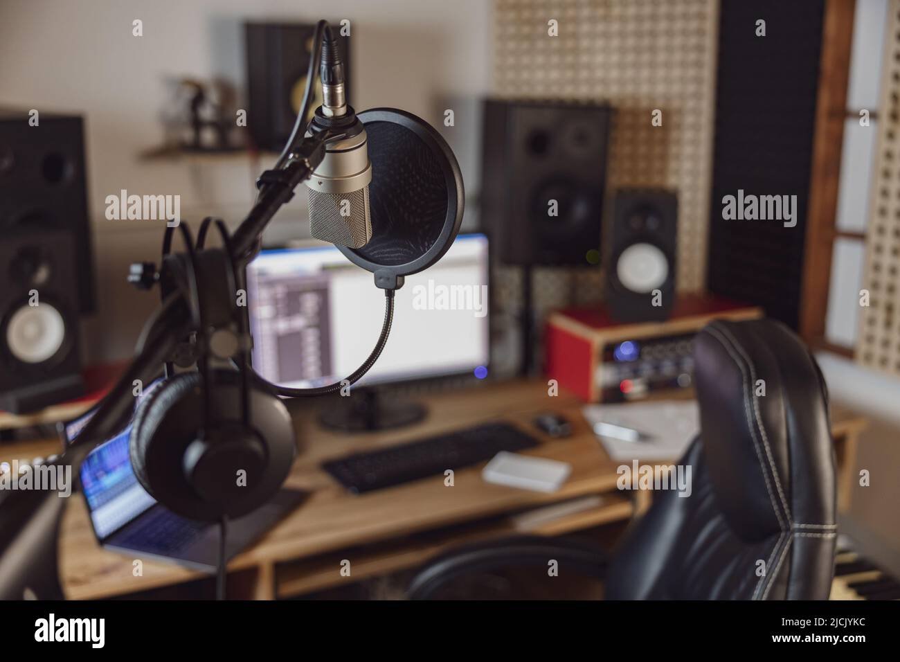 Concentratevi su microfono e cuffie professionali nel luogo di lavoro sfocato per lo studio di registrazione audio e broadcast Foto Stock