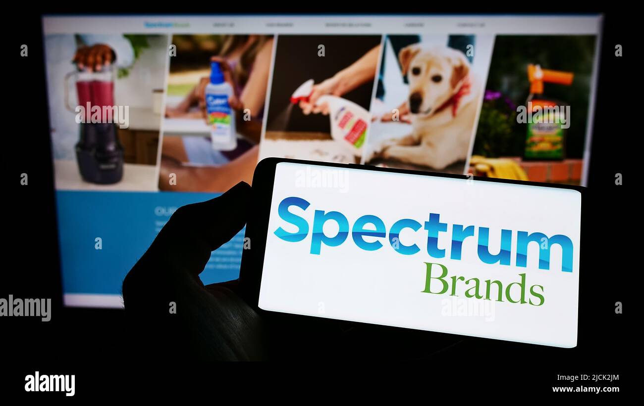 Persona che tiene il telefono cellulare con il logo della società americana Spectrum Brands Holdings Inc. Sullo schermo di fronte alla pagina web. Mettere a fuoco sul display del telefono. Foto Stock