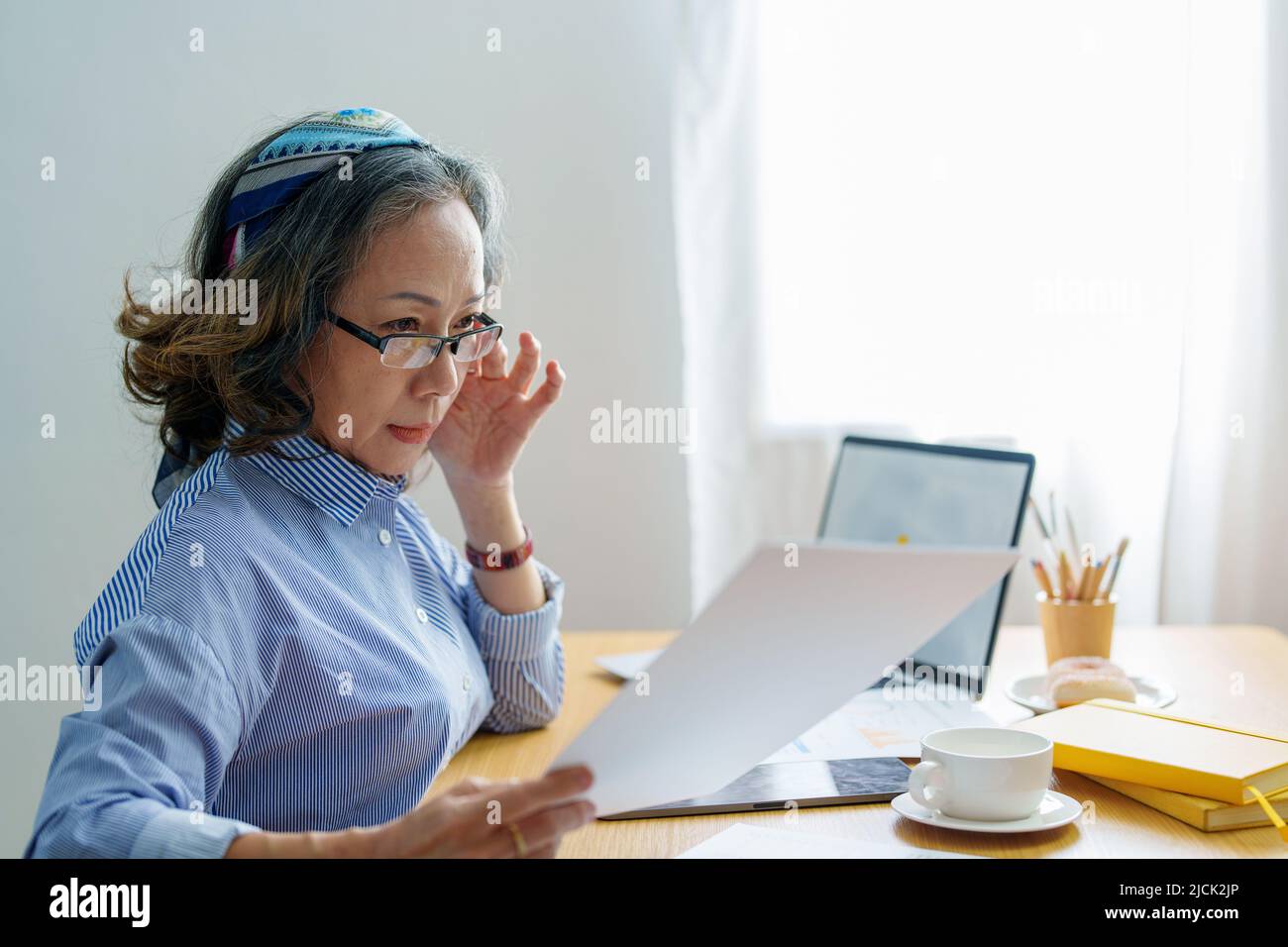 Ritratto di una donna anziana in possesso di un documento importante per verificare l'autenticità delle note sulla carta Foto Stock