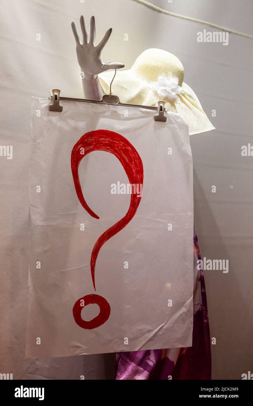 Manichino nella finestra di un negozio di moda che indossa un poster che mostra un grande punto interrogativo rosso. Bruxelles. Foto Stock