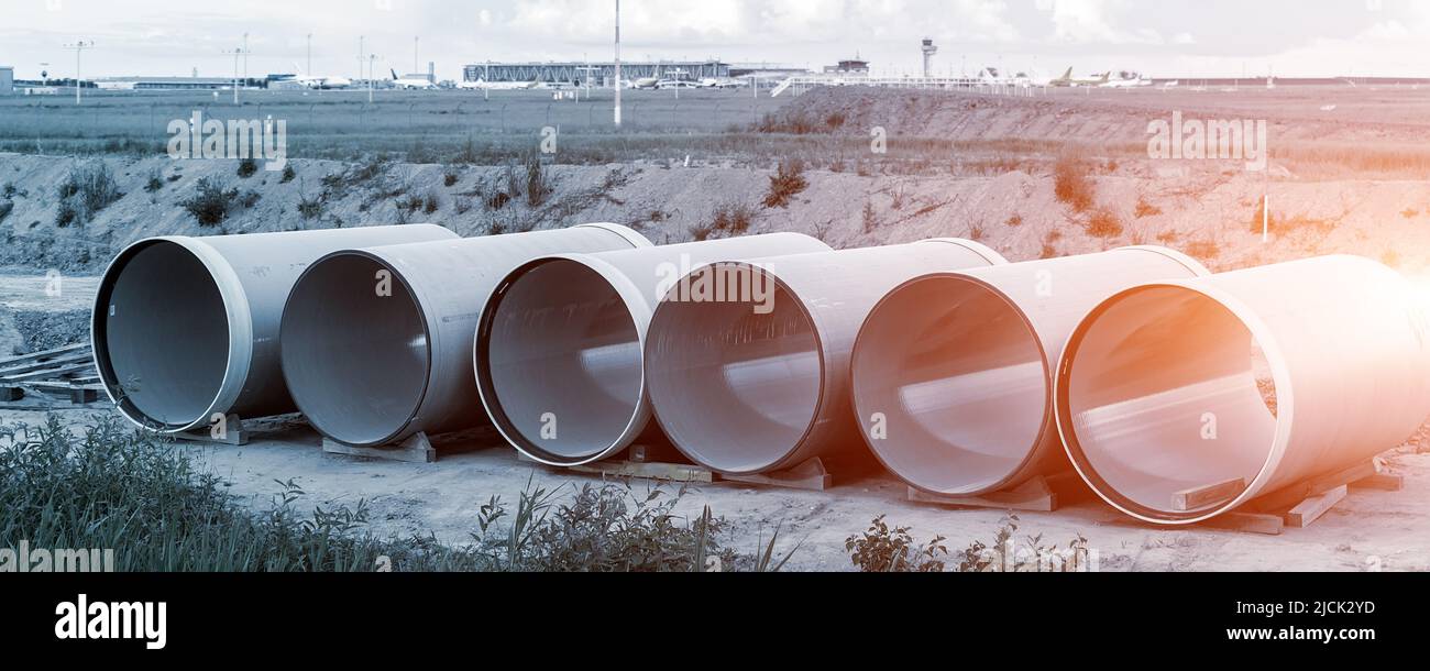 Stack di grandi tubi fognari in plastica vetroresina compositi frp presso il cantiere di costruzione del magazzino vicino all'aeroporto di Lipsia Halle su sfondo blu cielo Foto Stock