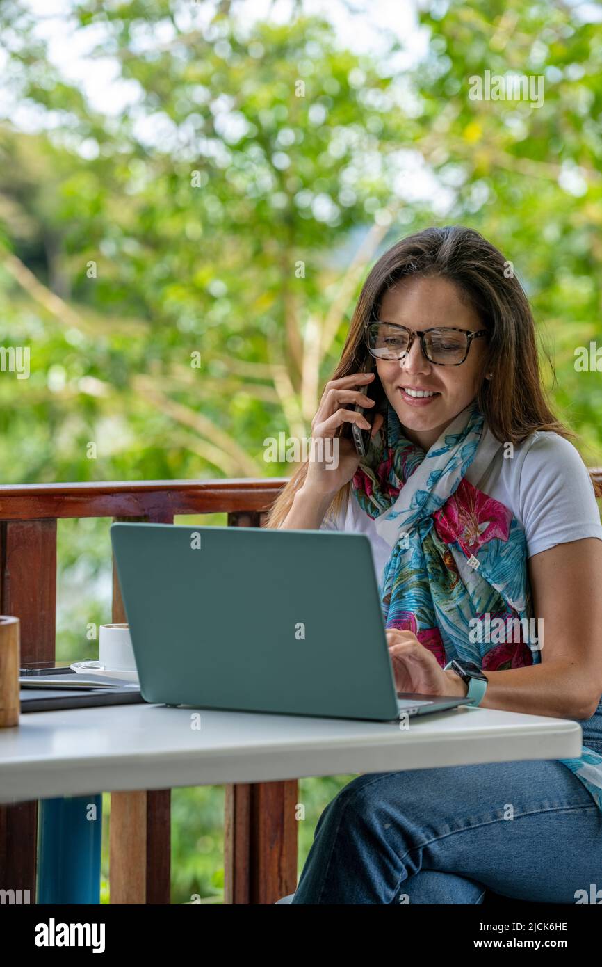 Giovane donna latino-americana che lavora sul suo laptop in un bar all'aperto mentre beve una tazza di caffè, Panama, America Centrale Foto Stock