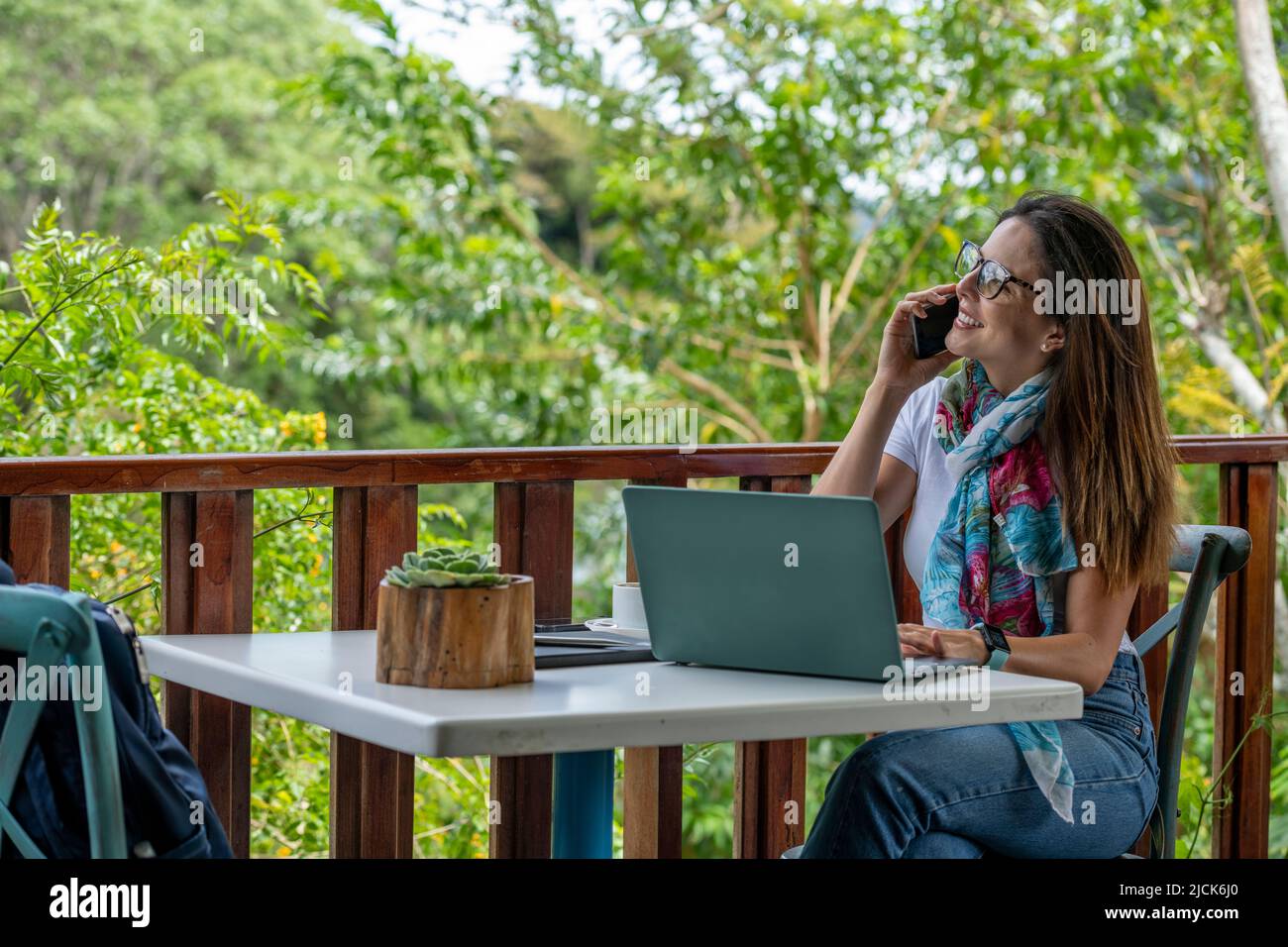 Giovane donna latino-americana che lavora sul suo laptop in un bar all'aperto mentre beve una tazza di caffè, Panama, America Centrale Foto Stock