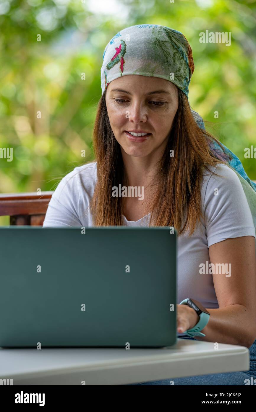 Giovane donna latino-americana che lavora sul suo laptop in un bar all'aperto mentre beve una tazza di caffè, Panama, America Centrale Foto Stock