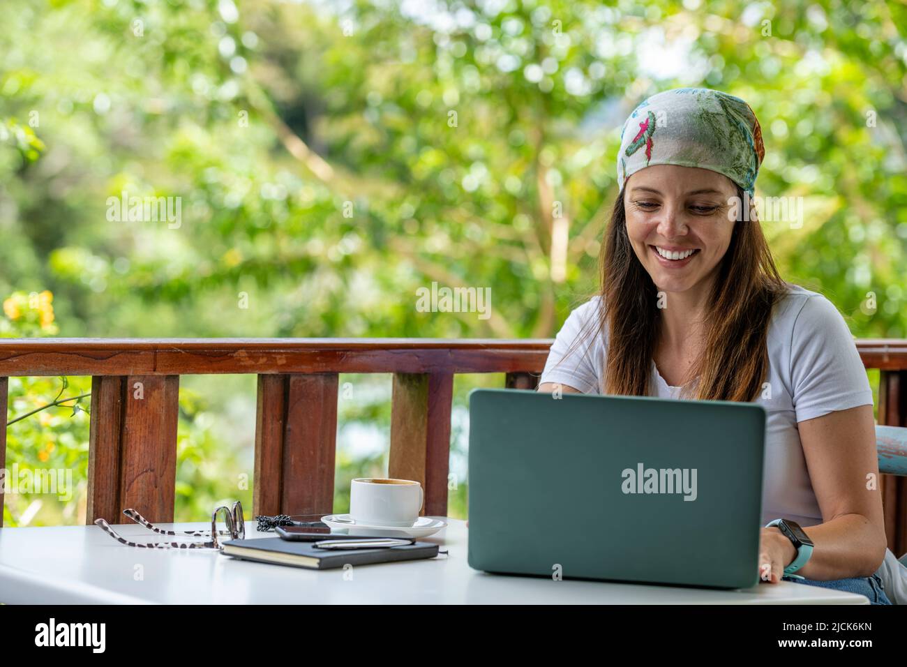 Giovane donna latino-americana che lavora sul suo laptop in un bar all'aperto mentre beve una tazza di caffè, Panama, America Centrale Foto Stock