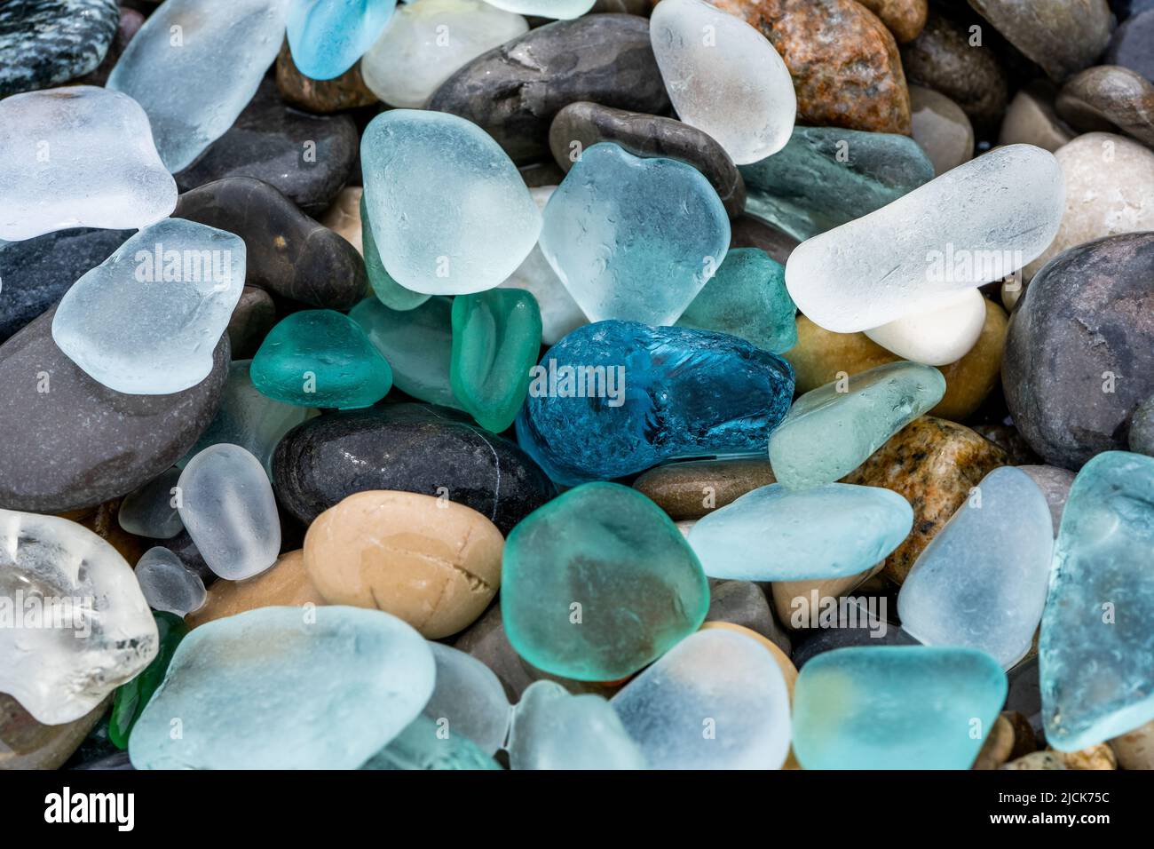 Vetro marino e pietre naturali sulla riva del mare. Azzurro acqua di mare limpida con onde. Vetro verde, blu lucido con ciottoli di mare multicolore in primo piano. Spiaggia sfondo estivo Foto Stock