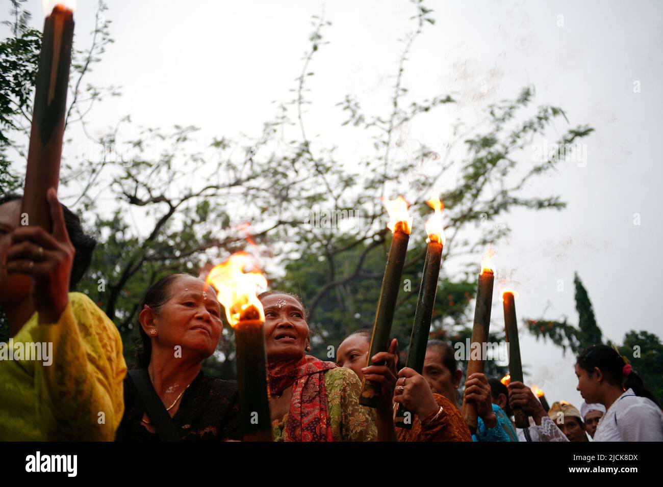 Donna anziana che porta la torcia tradizionale per una serie di eventi che celebrano la giornata di Nyepi a Kediri, Eastjava, Indonesia Foto Stock