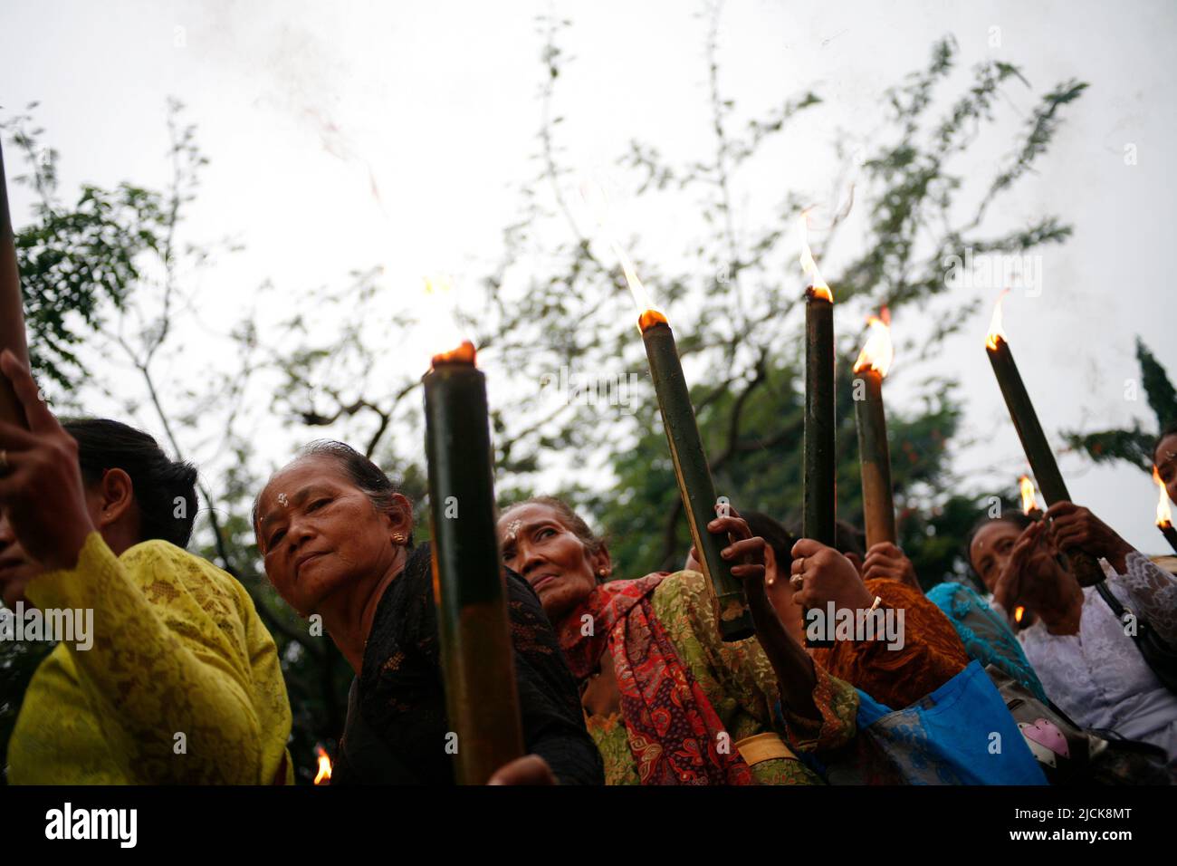 Donna anziana che porta la torcia tradizionale per una serie di eventi che celebrano la giornata di Nyepi a Kediri, Eastjava, Indonesia Foto Stock