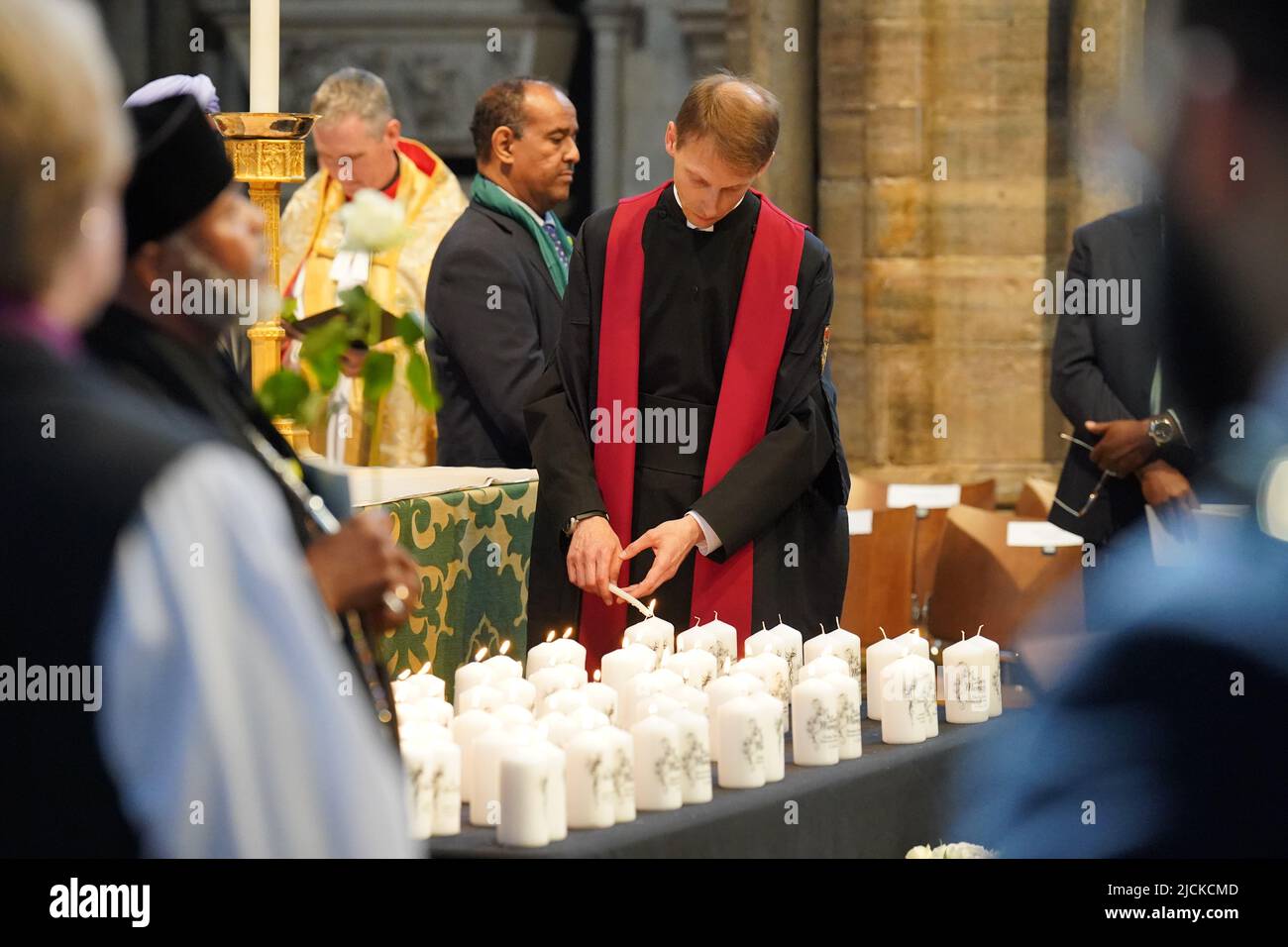 Un membro del clero accende le candele con i nomi delle vittime durante il servizio di commemorazione del fuoco di Grenfell all'Abbazia di Westminster a Londra, in ricordo di coloro che sono morti nel fuoco della torre di Grenfell il 14 2018 giugno. Data foto: Martedì 14 giugno 2022. Foto Stock