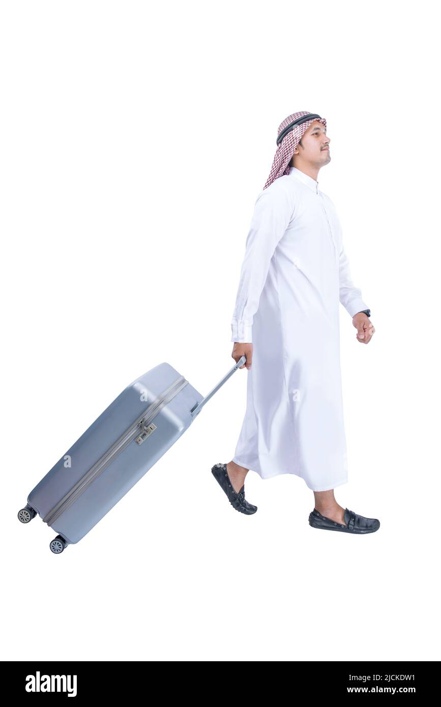 Uomo arabo che indossa keffiyeh camminando con una valigia per viaggiare isolato su sfondo bianco Foto Stock