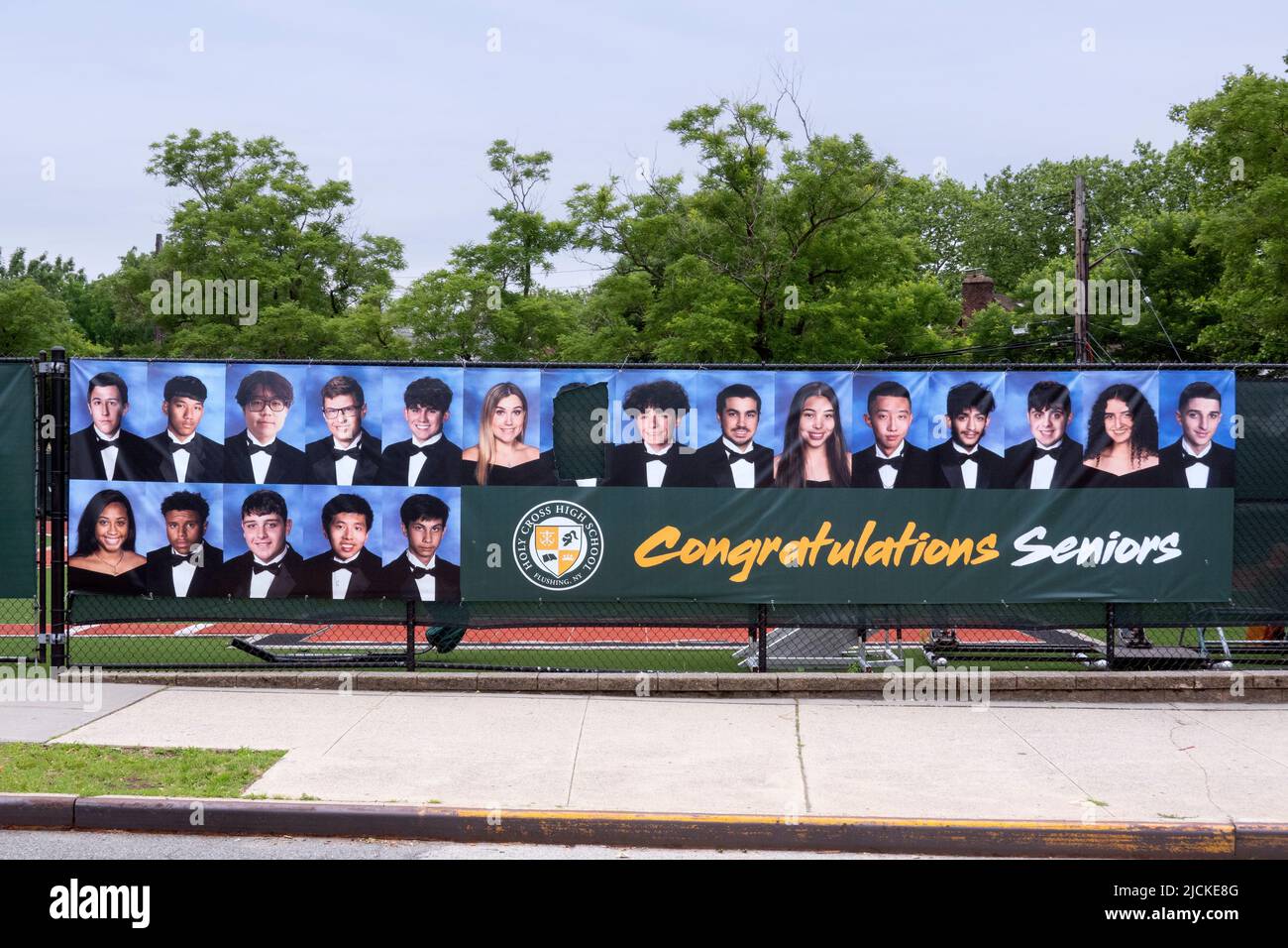 Su un banner che celebra i laureati della Scuola superiore della Santa Croce, qualcuno sembrava non gradire la loro foto e ritagliarla. A Flushing, Queens, New York. Foto Stock