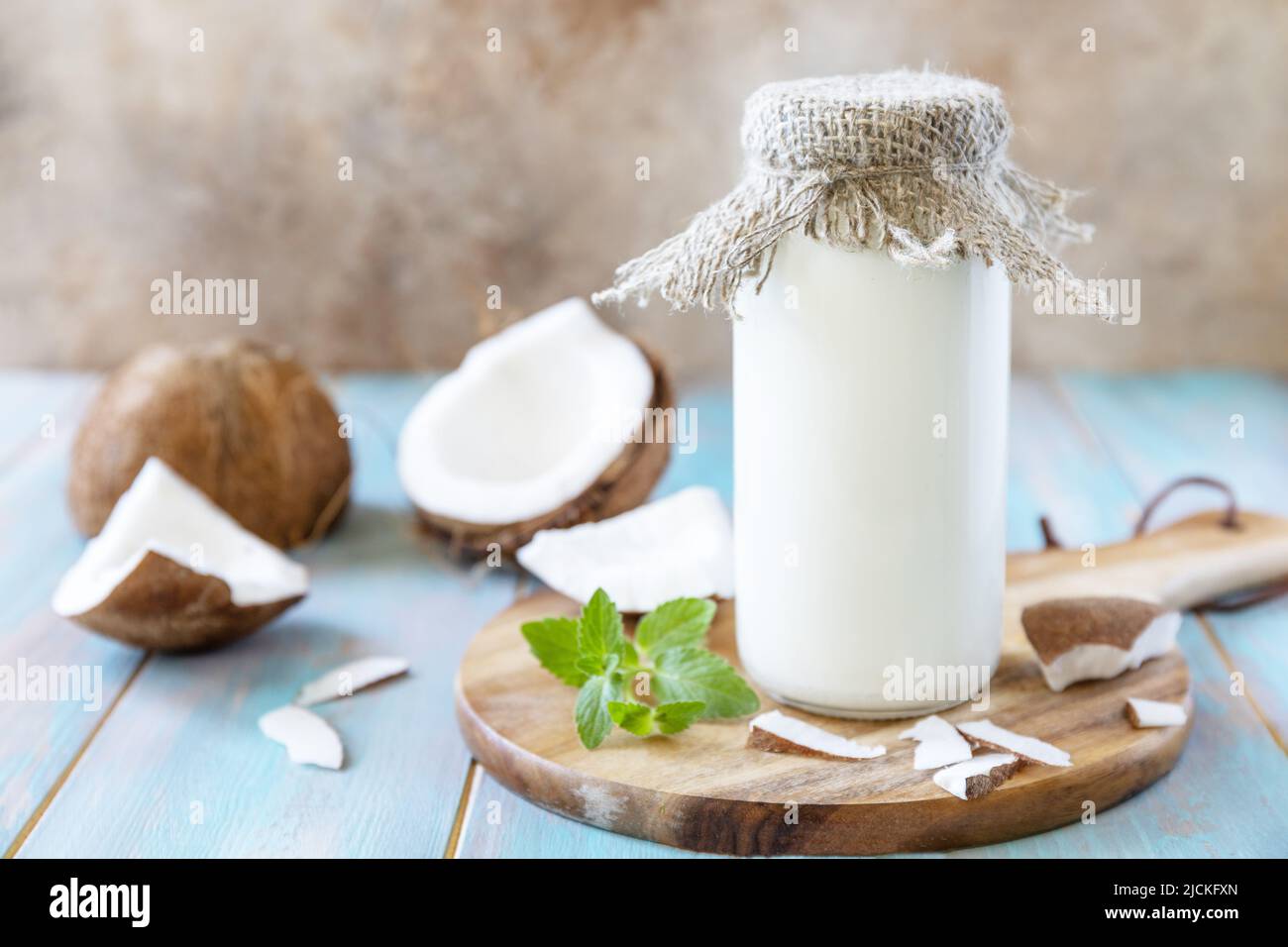 Latte alternativo vegano non caseario, contenuto sanitario. Latte di cocco biologico in una bottiglia su un tavolo rustico. Foto Stock