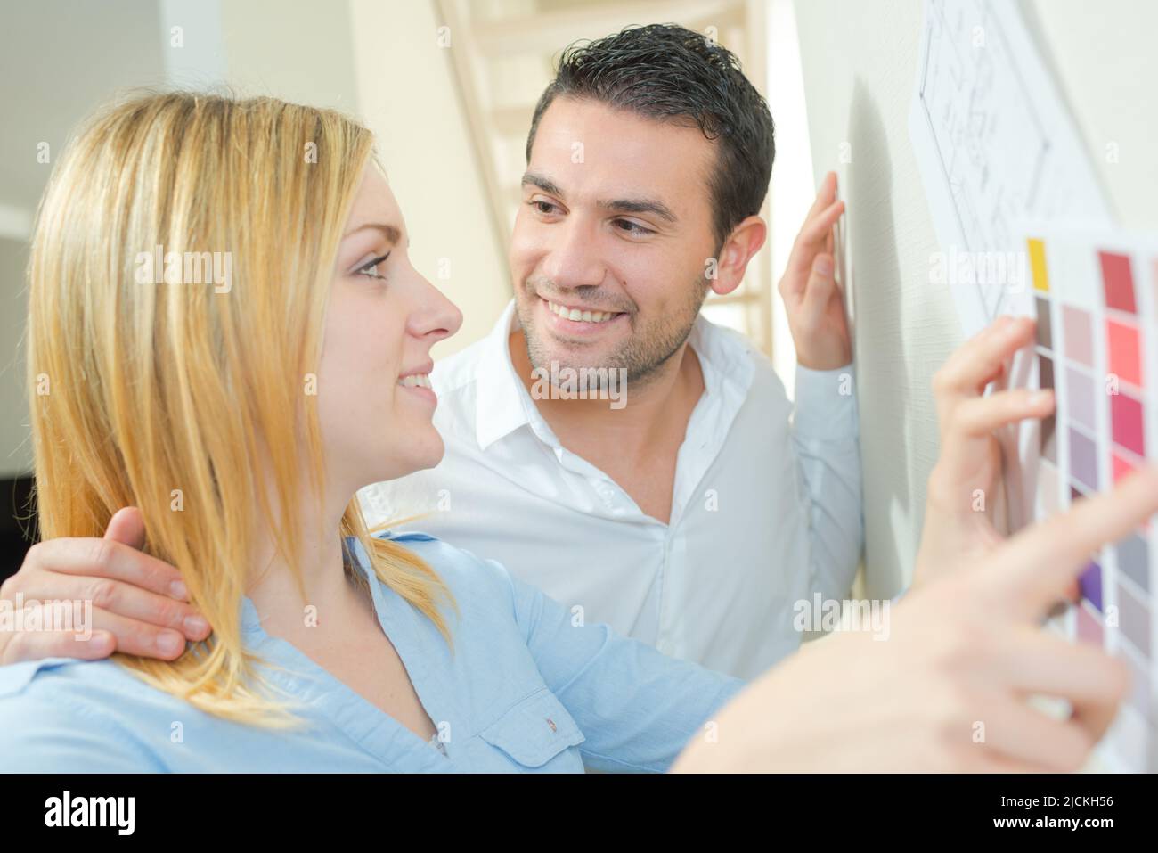 Coppia che tiene le carte della vernice contro la parete Foto Stock