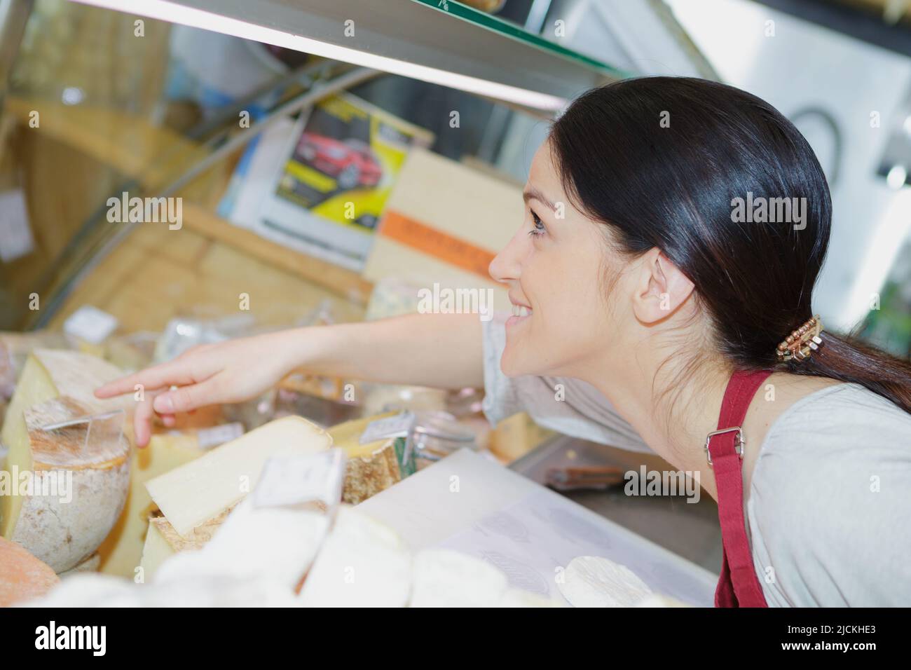 giovane donna che serve al banco del formaggio Foto Stock