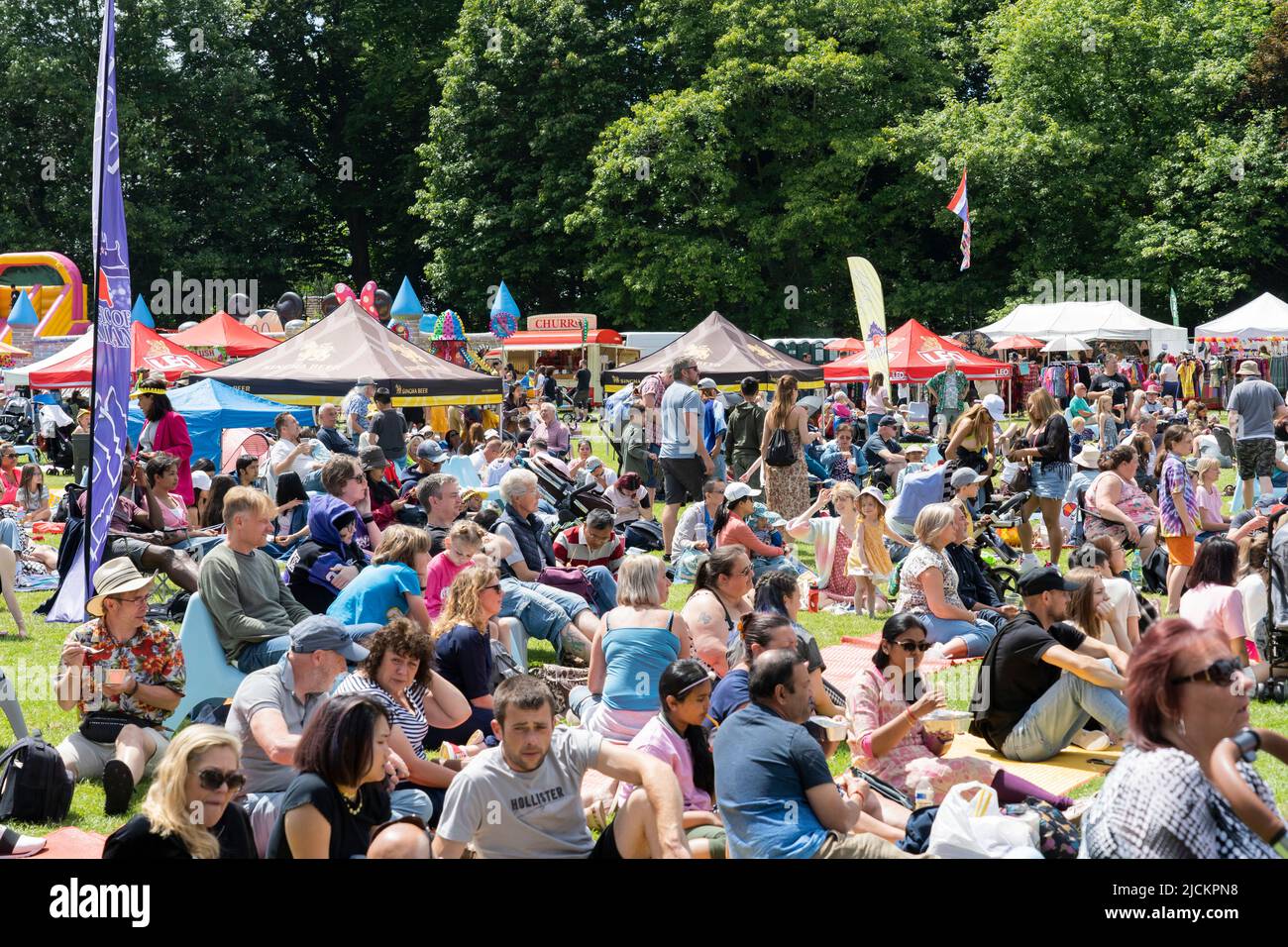 Le persone che si siedono e si godono il sole estivo al Magic of Thailand Festival al Basingstoke War Memorial Park. Giugno 12th 2022. Inghilterra Foto Stock
