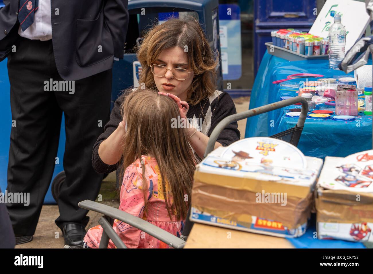 Pittore di volti al lavoro che decora il viso di un bambino. Concetto di face painting come intrattenimento per eventi. Foto Stock