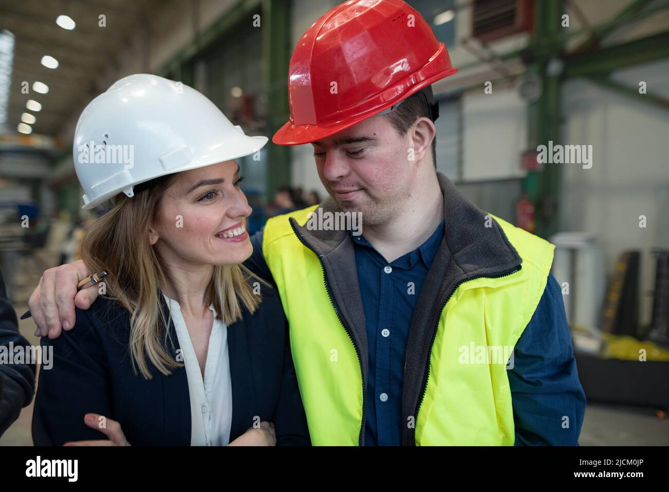 Giovane lavoratore con sindrome Down con manager che lavora in fabbrica industriale, concetto di integrazione sociale. Foto Stock